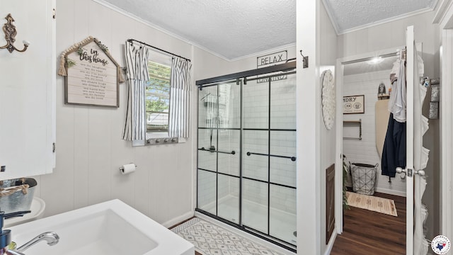 9216 W 7th St, Redwater, TX 75501 - bathroom featuring ornamental molding, a textured ceiling, a stall shower, a sink, and wood finished floors