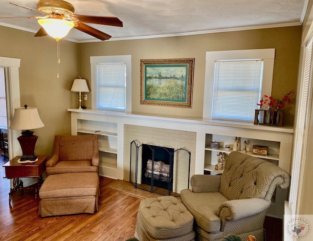 sitting room featuring hardwood / wood-style flooring, ceiling fan, crown molding, and a fireplace