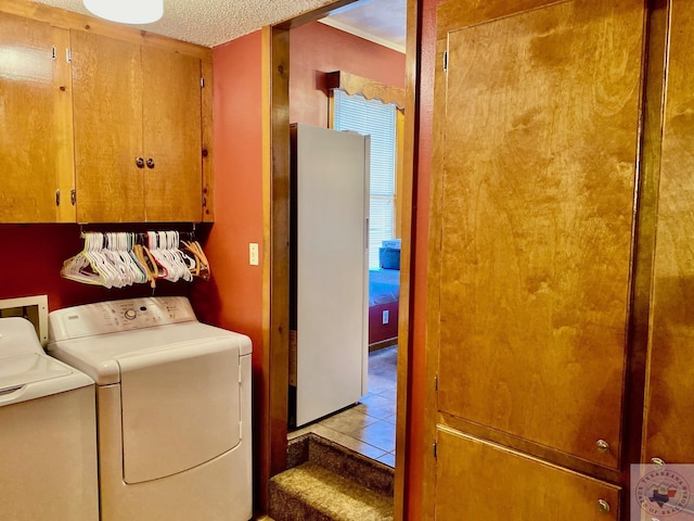 washroom with washing machine and dryer, a textured ceiling, light tile patterned floors, and cabinets