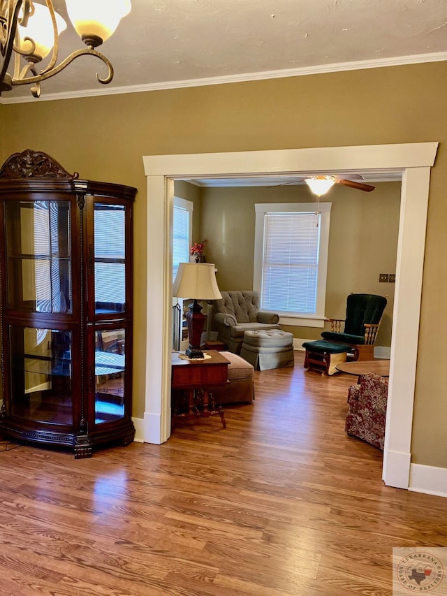 sitting room with crown molding, wood-type flooring, and an inviting chandelier