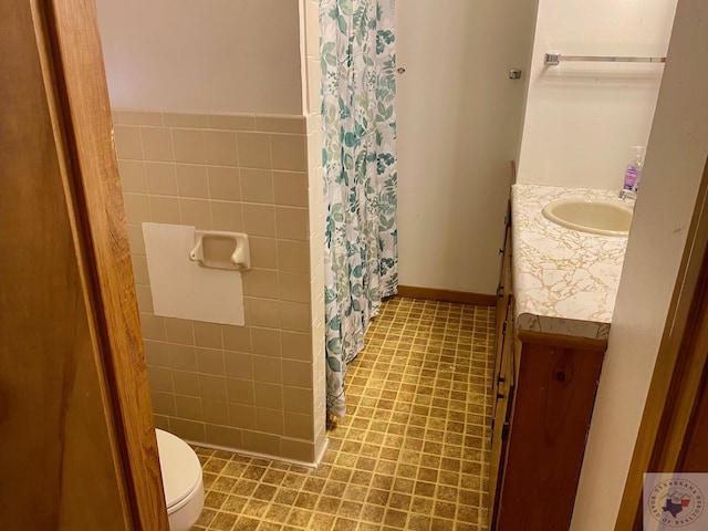 bathroom featuring toilet, tile walls, and vanity