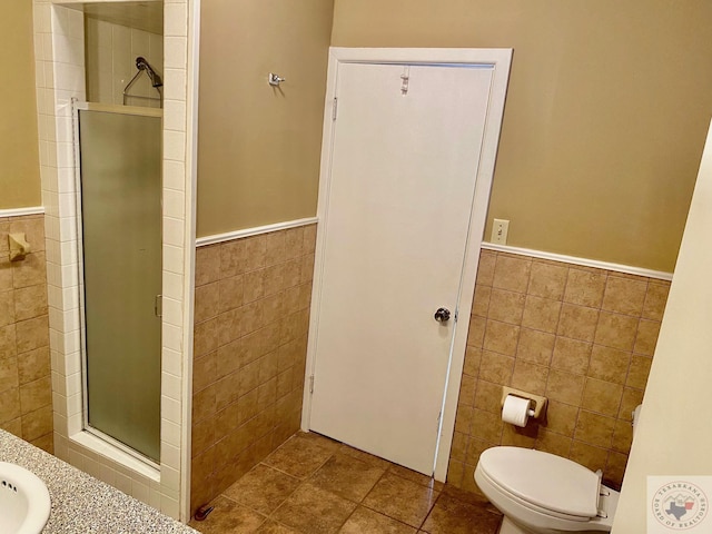 bathroom featuring a shower with shower door, tile walls, and toilet