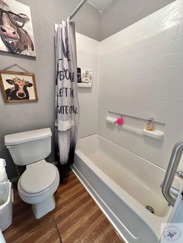 bathroom featuring shower / bathtub combination with curtain, toilet, and wood finished floors