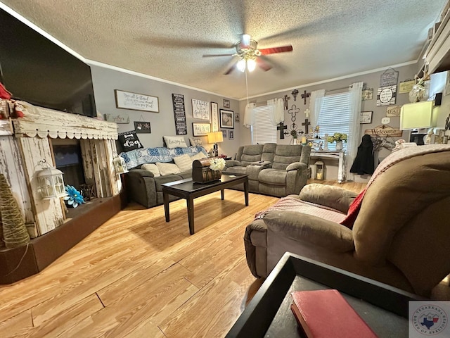 living area featuring a ceiling fan, a textured ceiling, ornamental molding, and wood finished floors