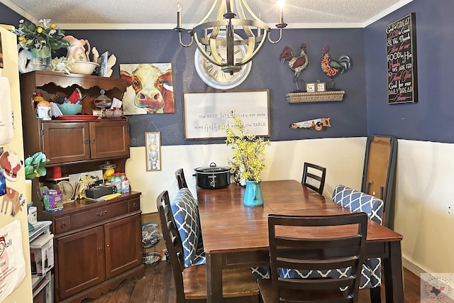 dining area with a textured ceiling, dark wood-type flooring, a chandelier, and crown molding