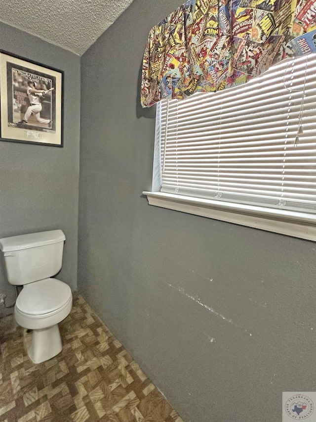 half bath featuring toilet and a textured ceiling