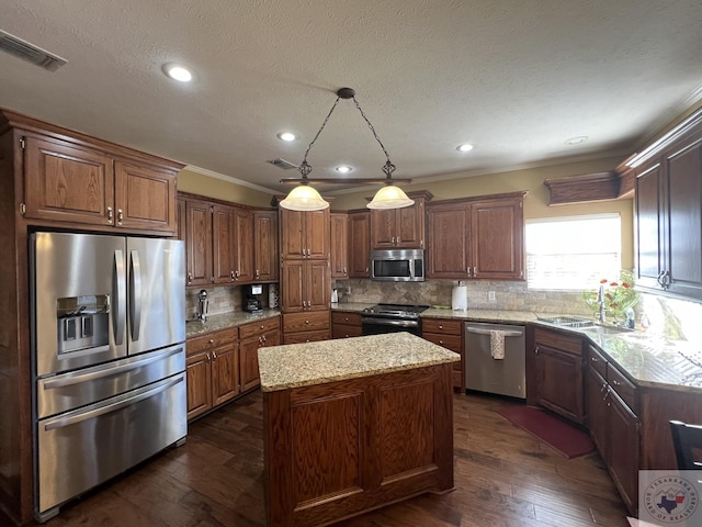 kitchen with sink, a kitchen island, decorative light fixtures, backsplash, and stainless steel appliances