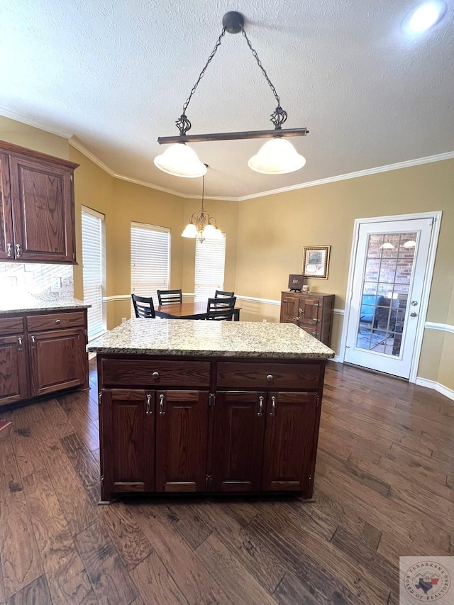 kitchen featuring dark wood-type flooring, pendant lighting, dark brown cabinetry, and a wealth of natural light