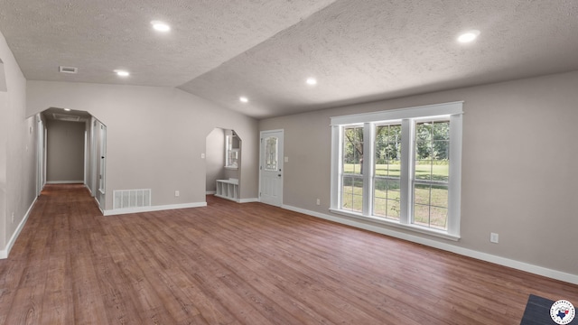 1911 Vanderbilt Rd, Texarkana, AR 71854 - unfurnished living room featuring arched walkways, a textured ceiling, wood finished floors, lofted ceiling, and recessed lighting