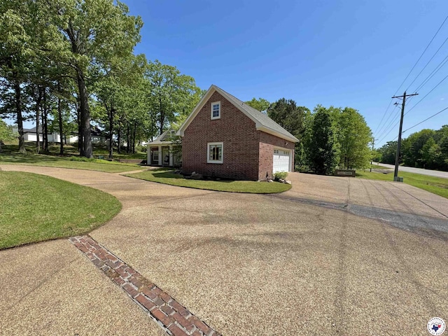 view of side of home featuring brick siding, driveway, and a lawn