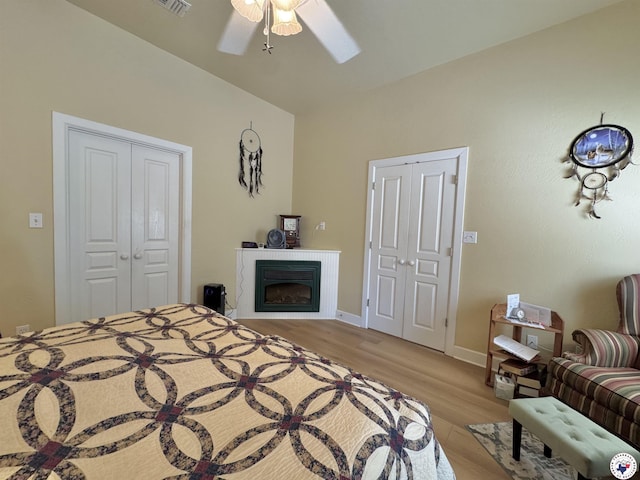 bedroom with baseboards, a closet, a fireplace, a ceiling fan, and light wood-style floors
