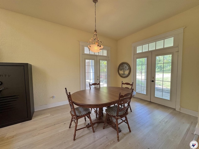 dining space with a textured wall, lofted ceiling, french doors, light wood finished floors, and baseboards