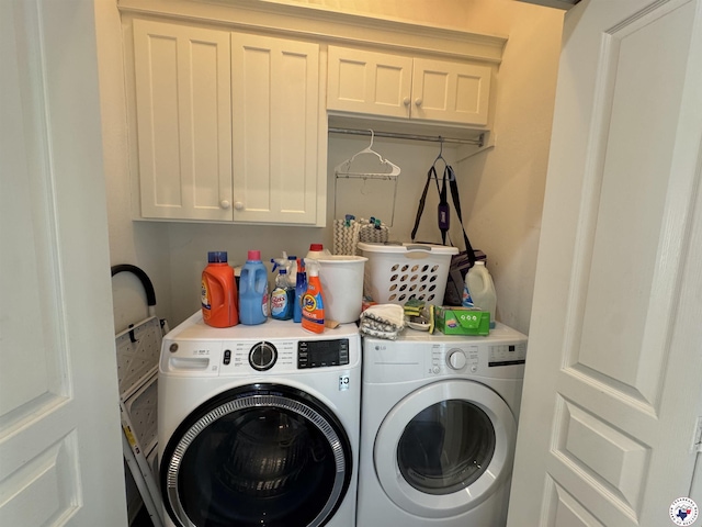 clothes washing area with washing machine and clothes dryer and cabinet space