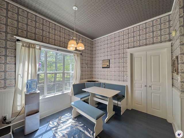 dining area featuring an ornate ceiling, wallpapered walls, a wainscoted wall, and wood finished floors