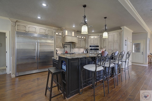 kitchen featuring light stone countertops, appliances with stainless steel finishes, a spacious island, pendant lighting, and a breakfast bar