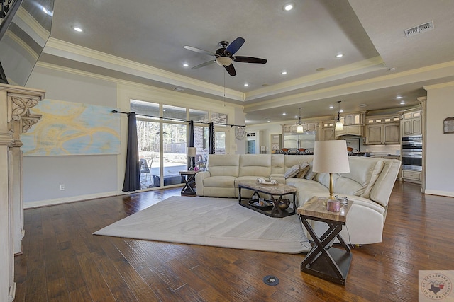 living room with ornamental molding, dark hardwood / wood-style floors, and a tray ceiling