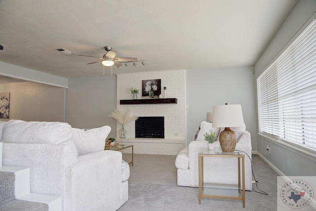 living area with carpet floors, a fireplace, visible vents, a ceiling fan, and baseboards