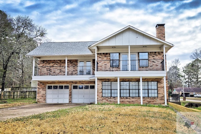 view of front of property featuring a balcony, driveway, a chimney, and brick siding