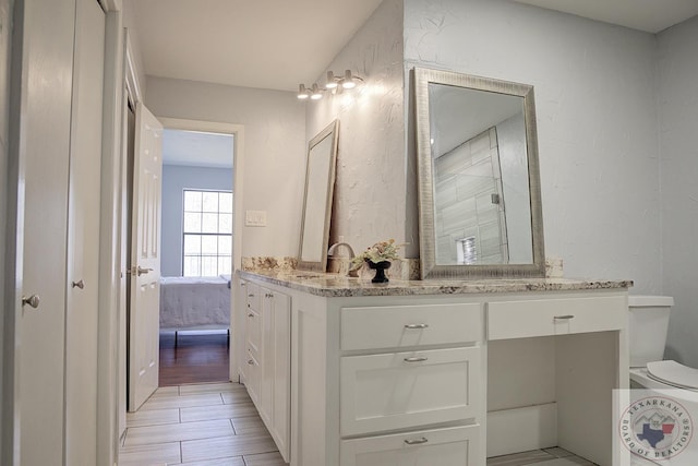 ensuite bathroom featuring a stall shower, a textured wall, vanity, and ensuite bathroom