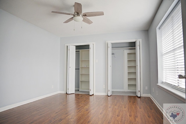 unfurnished bedroom with a ceiling fan, baseboards, multiple closets, and wood finished floors