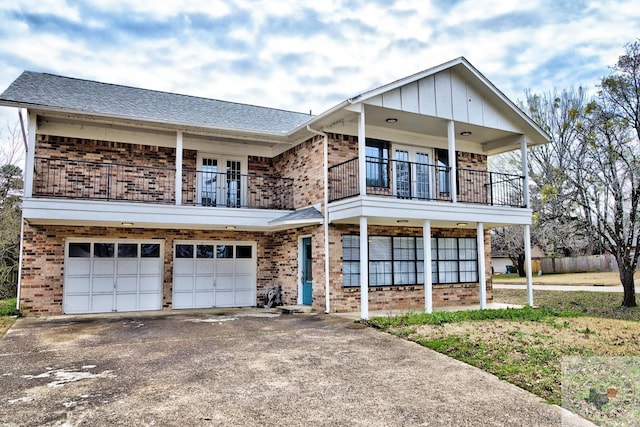 view of front of property featuring a balcony, a garage, brick siding, a shingled roof, and driveway