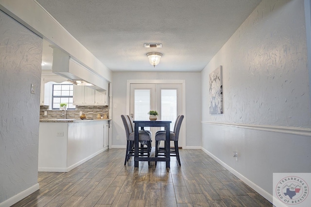 dining area with a textured ceiling, a textured wall, dark wood-type flooring, and visible vents