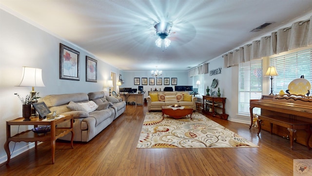 living room with a chandelier, crown molding, and wood-type flooring