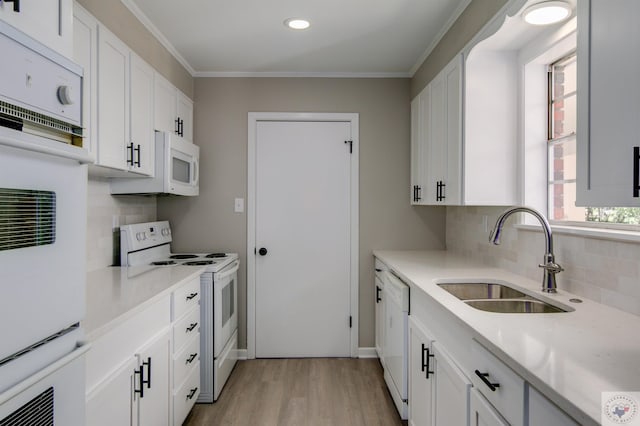 kitchen with white appliances, a wealth of natural light, white cabinetry, sink, and backsplash