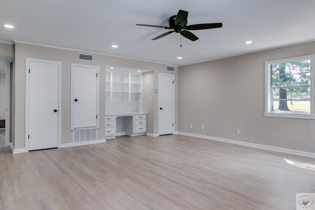 unfurnished living room with built in desk, ceiling fan, light hardwood / wood-style flooring, and crown molding