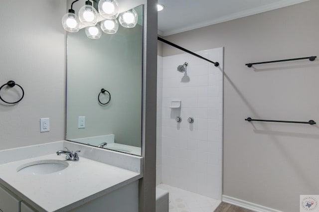 bathroom featuring a tile shower, vanity, and ornamental molding