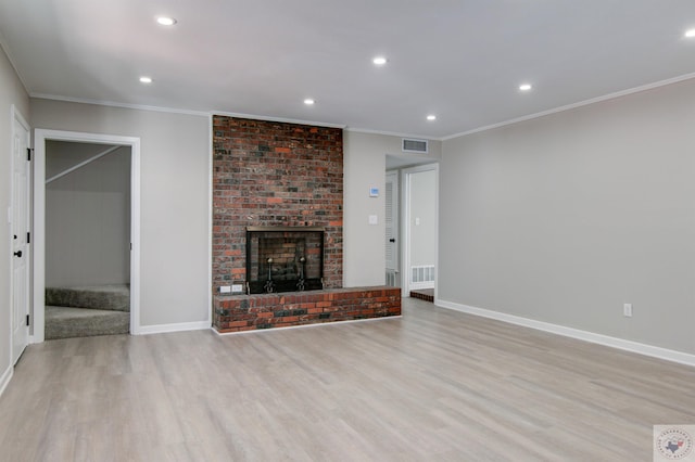 unfurnished living room with light hardwood / wood-style flooring, crown molding, and a fireplace