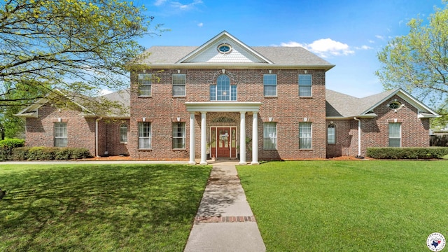 colonial house with a front lawn and brick siding