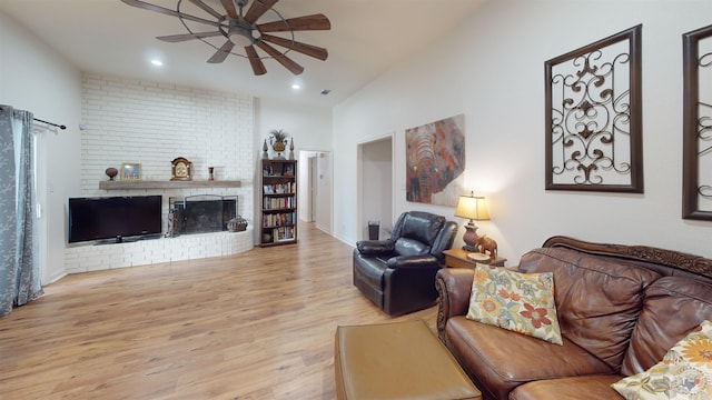 living room with ceiling fan, light hardwood / wood-style flooring, lofted ceiling, and a brick fireplace