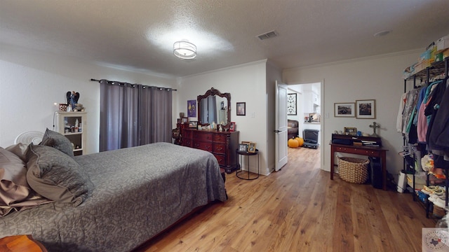 bedroom featuring hardwood / wood-style floors, a textured ceiling, and ornamental molding