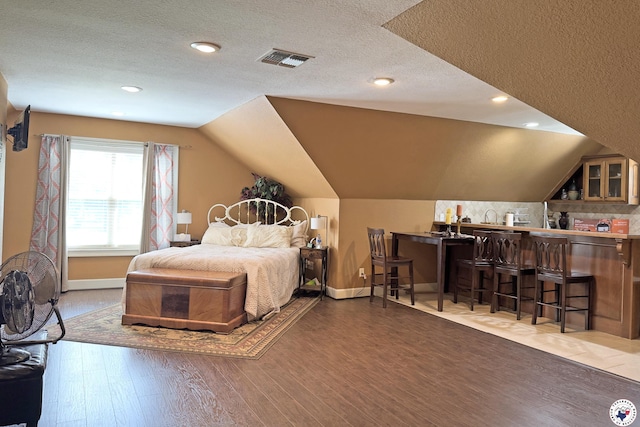 220 Quail Trl, Texarkana, TX 75501 - bedroom with vaulted ceiling, a textured ceiling, baseboards, visible vents, and wood finished floors