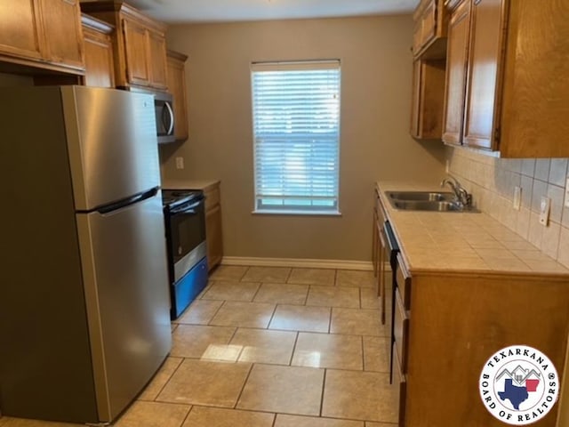 2415-2417 Laurel, Texarkana, AR 71854 - kitchen featuring appliances with stainless steel finishes, a sink, backsplash, brown cabinetry, and baseboards