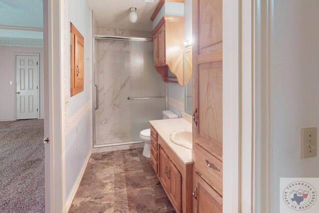 bathroom featuring a textured ceiling, toilet, a shower with door, and vanity