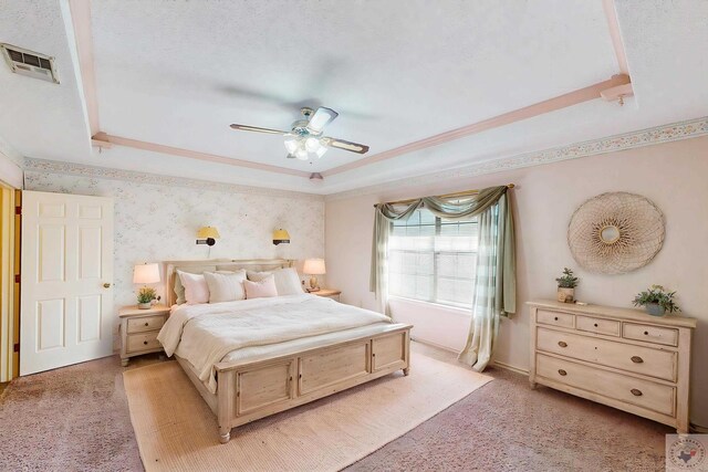 carpeted bedroom with ceiling fan, crown molding, and a tray ceiling