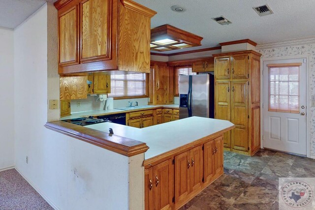 kitchen featuring a textured ceiling, black dishwasher, sink, stainless steel fridge, and kitchen peninsula