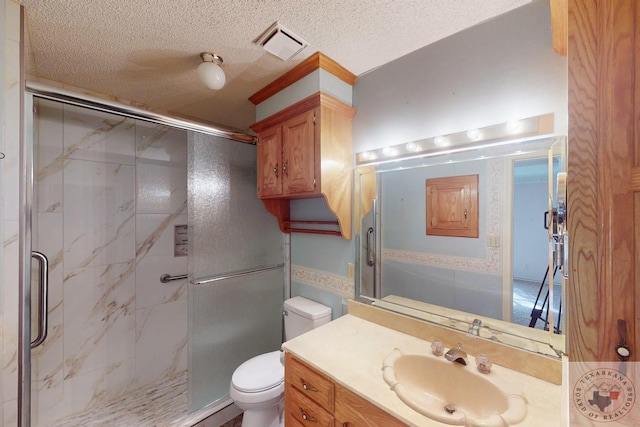 bathroom with vanity, a shower with shower door, a textured ceiling, and toilet