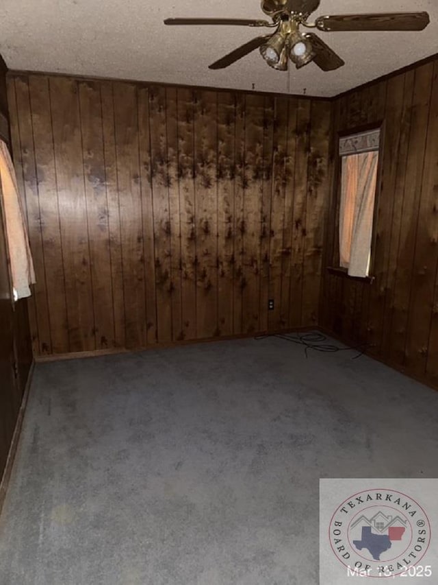 unfurnished room with wooden walls, carpet floors, and a textured ceiling