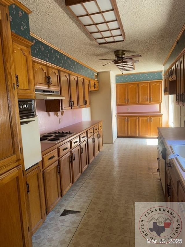 kitchen with wallpapered walls, ceiling fan, electric stovetop, under cabinet range hood, and white oven