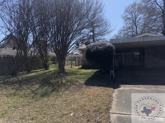 view of yard featuring a carport, driveway, and fence