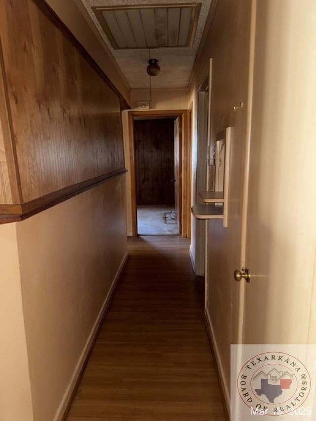 corridor with dark wood-type flooring, attic access, baseboards, and visible vents