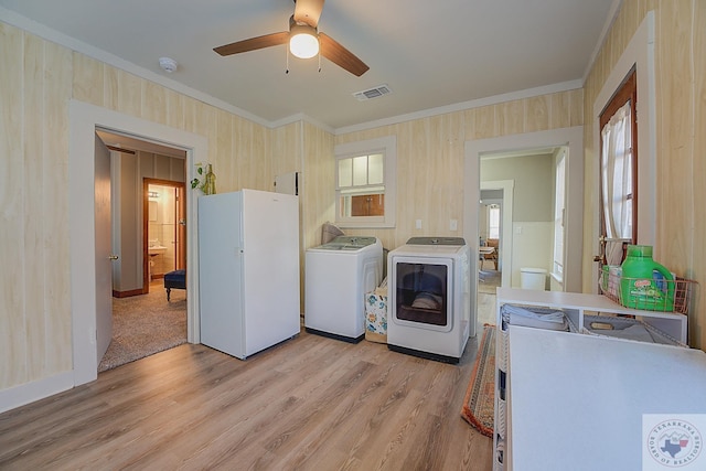 laundry room with crown molding, a healthy amount of sunlight, light hardwood / wood-style flooring, and washing machine and dryer