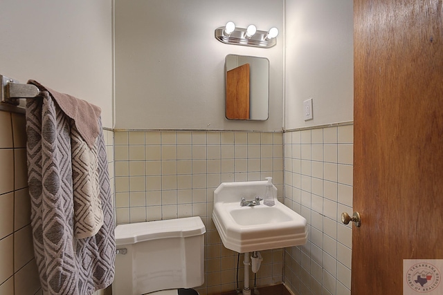 bathroom with sink, tile walls, and toilet