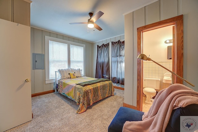 bedroom featuring ceiling fan, light colored carpet, electric panel, and ensuite bath