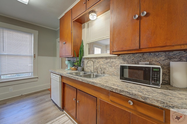 kitchen with sink, light hardwood / wood-style floors, ornamental molding, and white dishwasher