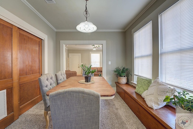 carpeted dining space featuring crown molding