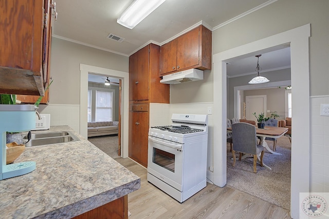 kitchen with light wood-type flooring, sink, ornamental molding, pendant lighting, and white gas range